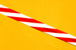 Ein rot-weiss gestreiftes Klebeband auf gelbem Hintergrund