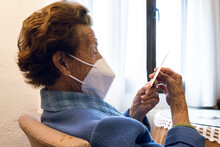 Senior Woman In Protective Face Mask Looking At Photograph
