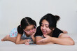 Asian mother explain something to her daughter while watching movie using mobile phone