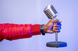 © Westend61 - Male influencer's hand holding microphone over purple wall at studio