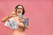 © denis_vermenko - Happy winner! Image of a mature senior happy old woman standing isolated over pink background, holding money.