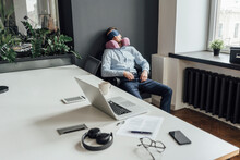 Tired Male Entrepreneur With Neck Pillow And Eye Mask Napping In Office