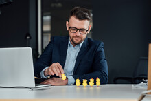 Male Entrepreneur With Laptop Holding Baby Chicken Toy In Office
