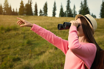 Wall Mural - Young woman with binoculars outdoors on sunny day