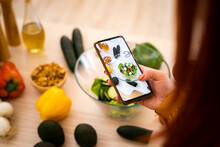 Woman Photographing Salad Bowl Through Mobile Phone At Table