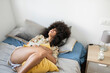 © Westend61 - Smiling afro woman lying on bed at home