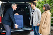 © Minerva Studio - Senior porter unloading a couple's baggage from their car
