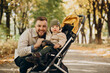 © Petro - Father with little son walking in baby stroller in autumnal park