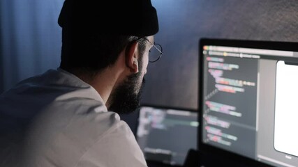 Young man mobile developer writes program code on a computer, programmer work in home office.
