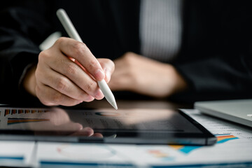 Canvas Print - Close up of Businesswomen or Accountant using a digital tablet with analyzing business report graph and finance chart at the workplace, financial and investment concept.