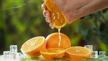 Hand squeezing orange on nature background. Organic citrus juice close-up. Spa treatments. Skincare, cosmetics and beauty concept.