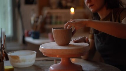 Poster - Handmade ceramics creation. Process of shaping and moulding pottery vase in studio with concentrated young female artist busy at work. Woman ceramist sculpturing clay jug on wheel in workshop space