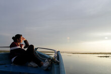 Young Woman Sitting Alone On A Boat Enjoying Morning Sunlight Over The Sea. Person Relax On Boat. 
