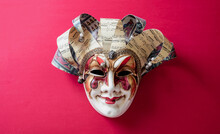 Carnival Venetian Harlequin Mask On Red Color Background. Traditional Festival Disguise.