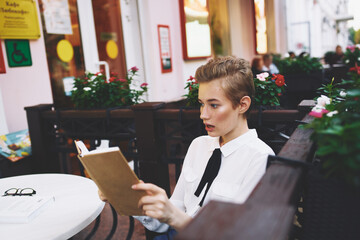 Wall Mural - student with a book in his hands outdoors in a summer cafe rest communication