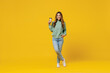 Full body young smiling woman 30s in green knitted sweater hold takeaway delivery craft paper brown cup coffee to go isolated on plain yellow color background studio portrait People lifestyle concept