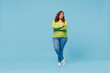 Full body confident happy young chubby overweight plus size big fat fit woman wear green sweater hold hands crossed folded isolated on plain blue background studio portrait. People lifestyle concept.