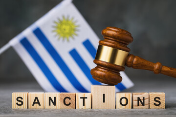 Wall Mural - Judge gavel, wooden cubes with the text on the background of the flag of Uruguay, concept on the topic of sanctions in Uruguay