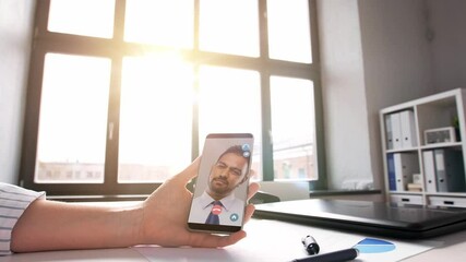 Wall Mural - remote job, technology and people concept - hand of woman holding smartphone and having video call with indian male colleague at home office