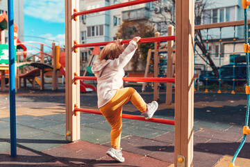 A small child is climbing a children's sports wall. View from the back. The concept of children's games and development