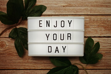 Wall Mural - enjoy your day text on lightbox on wooden background