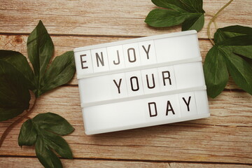 Wall Mural - enjoy your day text on lightbox on wooden background