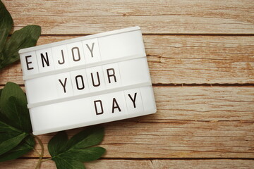 Wall Mural - enjoy your day text on lightbox on wooden background