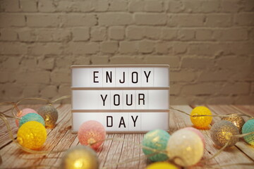 Wall Mural - enjoy your day text on lightbox on wooden background