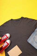 Wall Mural - Blank t-shirt, jeans, sneakers and carton sheet on yellow background