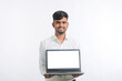 © PRASANNAPIX - Young indian man showing laptop screen with copy space on white background.