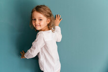 Smiling Girl Leaning On Blue Wall