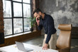 © Face Stock - Busy male office employee standing near office desk, talking on the smartphone and checking on laptop, businessman in smart casual take a call on mobile, manager has pleasant phone conversation