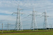 © Pokoman - power lines over an agricultural field. A high-voltage tower installed in a field with grain crops.