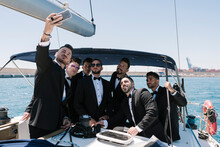 Man Taking Selfie With Male Friends Through Mobile Phone In Yacht