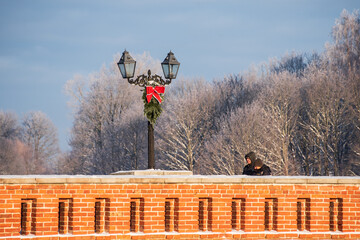 Poster - Lantern with Christmas decoration on a sunny winter day on old brick bridge in Kuldiga, Latvia