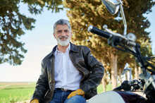Smiling Man Wearing Biker Jacket Sitting On Motorcycle