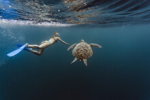 Indonesia, Bali, Underwater View Of Female Diver Swimmingalongside Lone Turtle