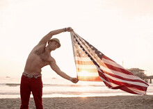 Shirtless Man Blowing Flag On Santa Monica Beach