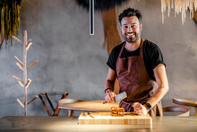 Smiling Chef With Meat Cleaver Standing By Food In Commercial Kitchen