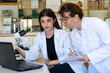 © Westend61 - Female scientist writing on document while discussing with colleague over laptop