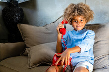 Boy With Toy Phone Sitting On Sofa At Home