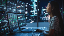 Portrait Of A Financial Analyst Working On Computer With Multi-Monitor Workstation With Real-Time Stocks, Commodities And Exchange Market Charts. Businesswoman At Work In Investment Broker Agency.