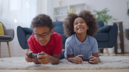 Wall Mural - Two happy african american kids playing video game with joysticks, home leisure