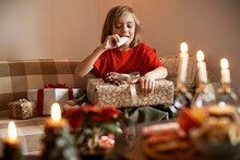 Boy Sitting On Sofa With Christmas Present And Eating