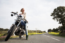 Smiling Female Biker Looking Away While Sitting On Motorcycle