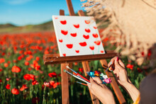 Female Artist With Paint On Palette By Canvas At Poppy Field