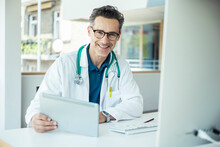 Smiling Male Doctor With Digital Tablet At Office