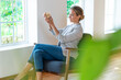 © Westend61 - Female entrepreneur holding wooden object while sitting on armchair at office