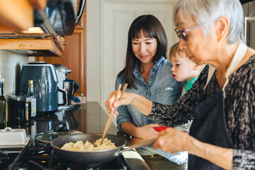 woman with son looking at mother cooking chinese dumplings