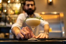 Waiter Giving Thyme Garnished Drink At Bar Counter